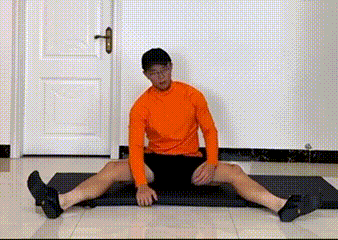 Man seated with legs spread doing a side stretch - post-workout back cooldown
