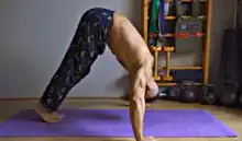 Person doing pike shoulder press in a bodyweight shoulder workout.