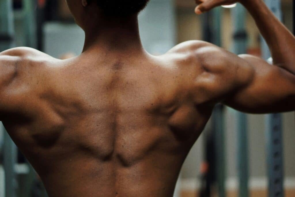Muscular man showing back muscles - beginner calisthenics back workout at home