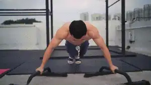 Man performing angled parallette chest squeeze push-up for exercises inner chest.