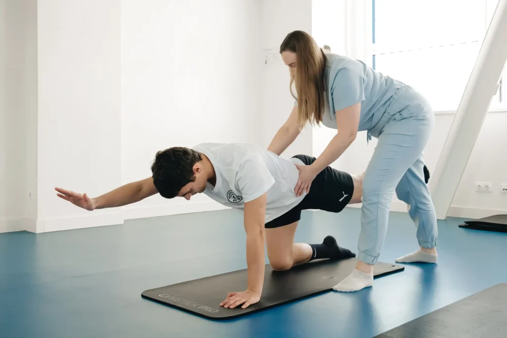 Bird dog stability drill as key lower back exercises, trainer correcting posture for proper hip and spine control