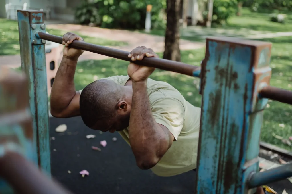 Man performing Bodyweight Tricep Extensions on outdoor workout bar, triceps exercises for upper arm muscle training