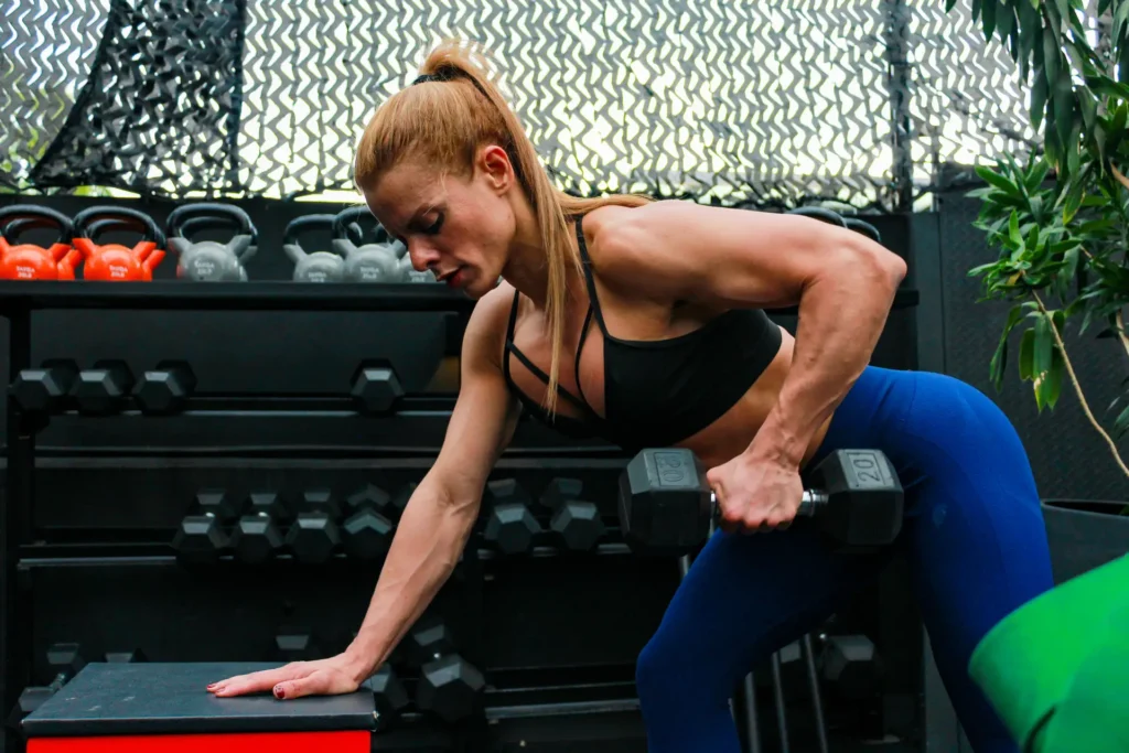 Woman performing a dumbbell three-point row, one of the staple teres major and minor exercises prioritizing teres major for back