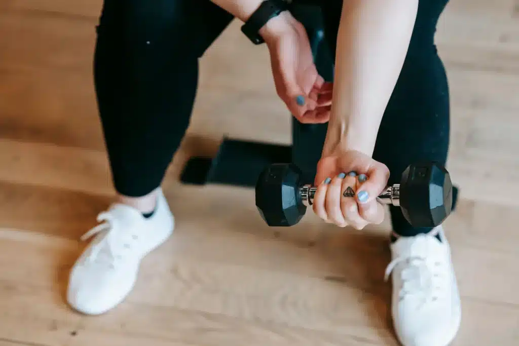 a woman performing a seated dumbbell wrist curl as part of effective home forearm exercises