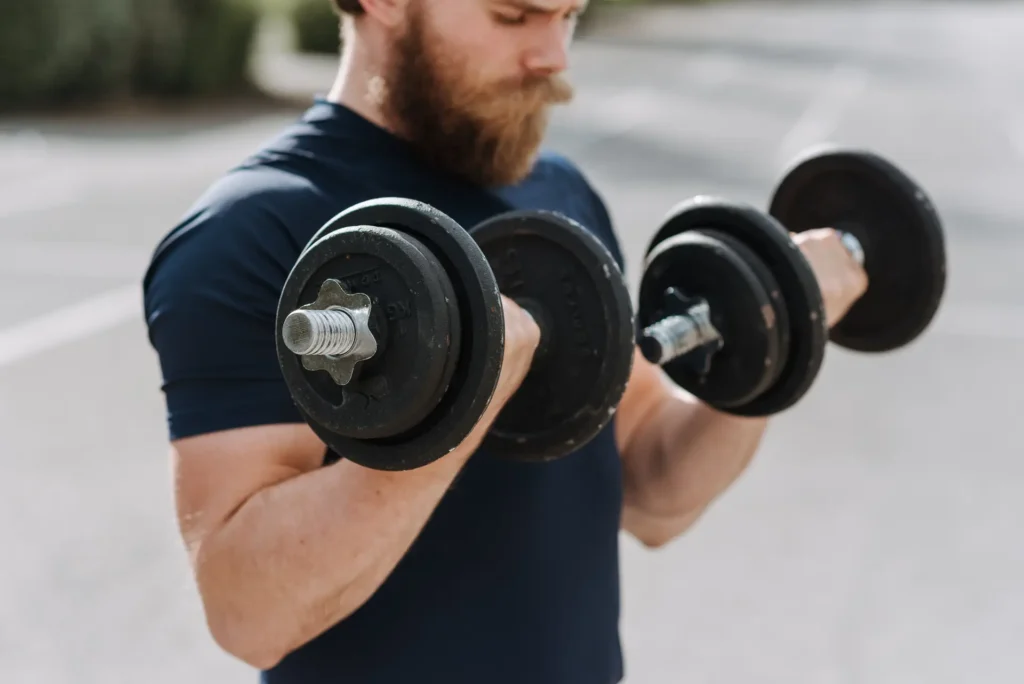 A man doing standing dumbbell curls, core bicep exercises for arm training