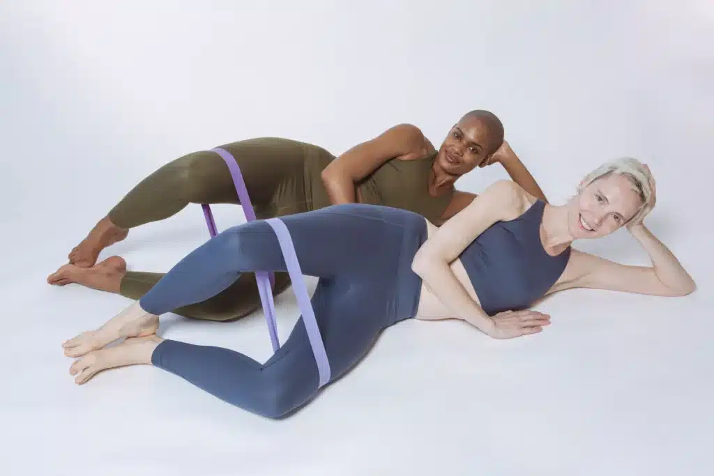 Two women performing banded clamshells as effective Gluteus Medius Exercises