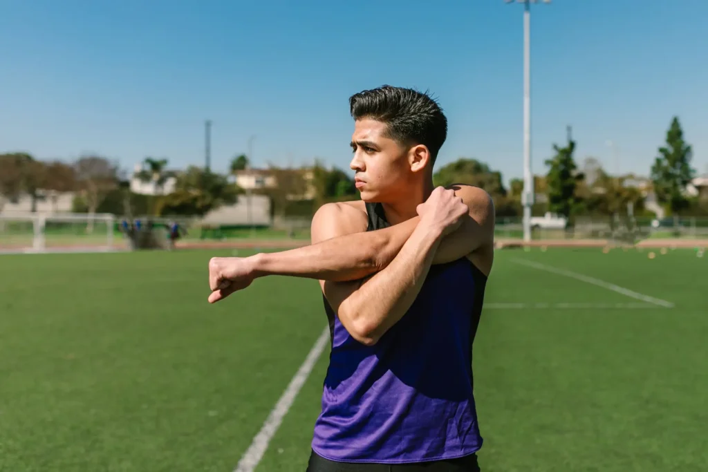 Male athlete doing cross-body shoulder stretch to prepare for rotator cuff exercises