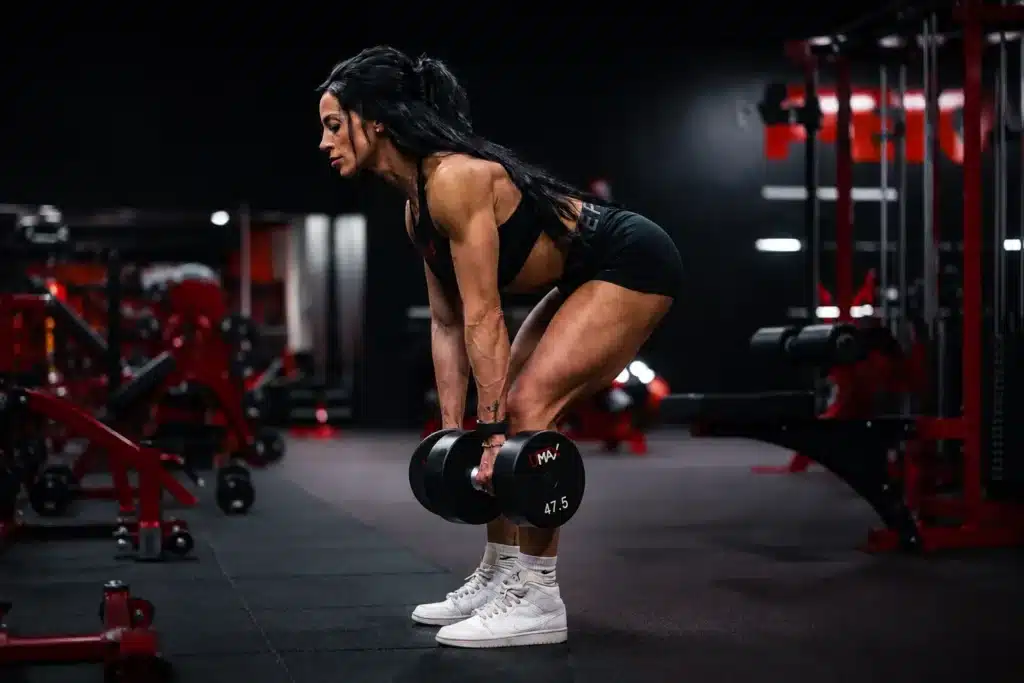 Woman performing dumbbell Romanian deadlift, one of effective semimembranosus exercises