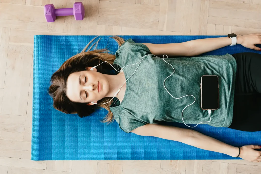 A woman lies on a yoga mat resting after working out.