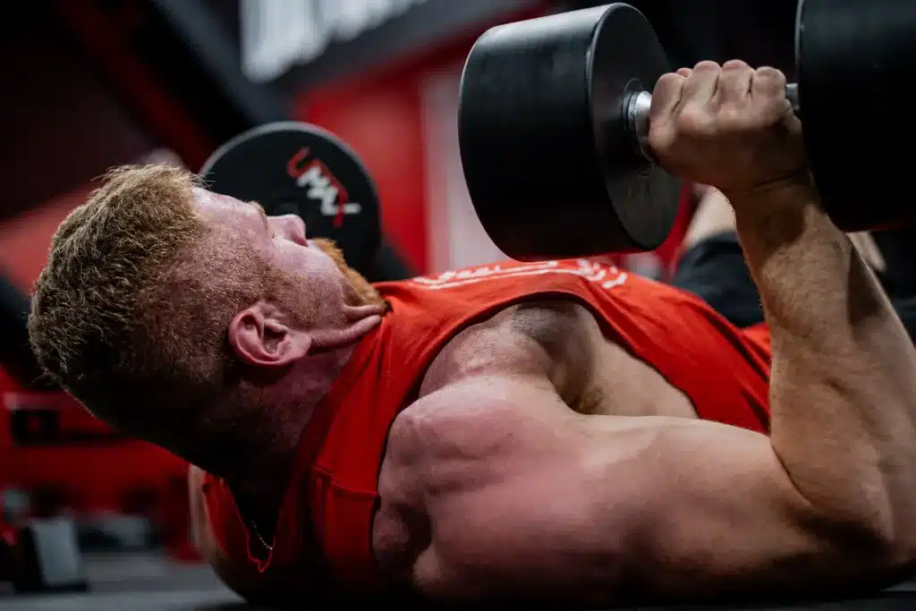 A man performing the dumbbell floor‑press